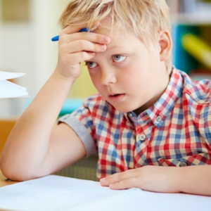 Un petit garçon à l'école, profondément concentré, réfléchissant avec un crayon en main.