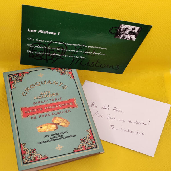 Une boîte de croquants de Provence fermée, accompagnée de la petite carte Les Mistons pour y écrire un message de l'expéditeur.